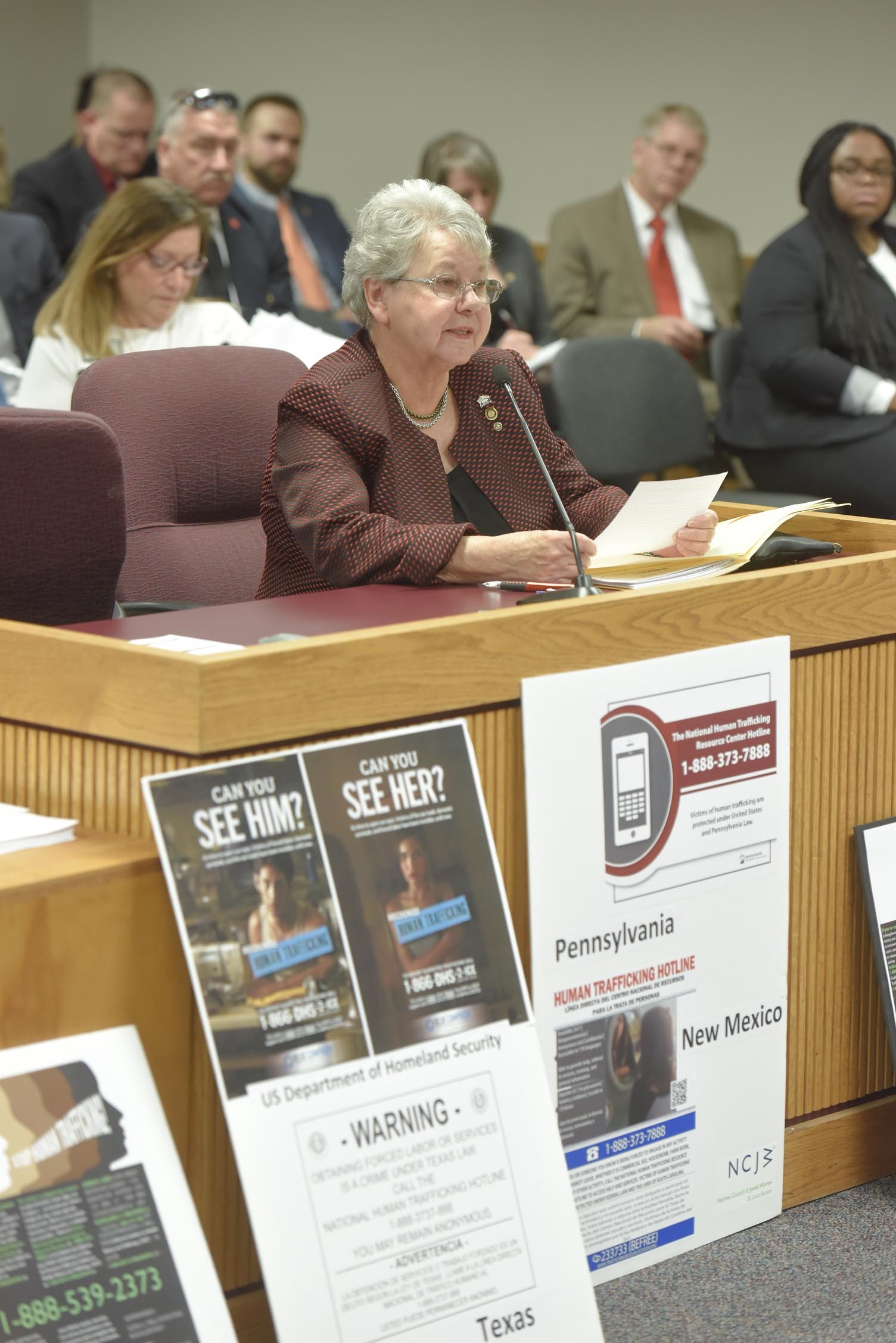 Representative Cloria Brown presents House Bill 261 that would require the creation and placement of posters offering help to human trafficking victims. In front of her are examples of posters from some of the 28 other states that have passed a similar law. (photo; Tim Bommel, Missouri House Communications)